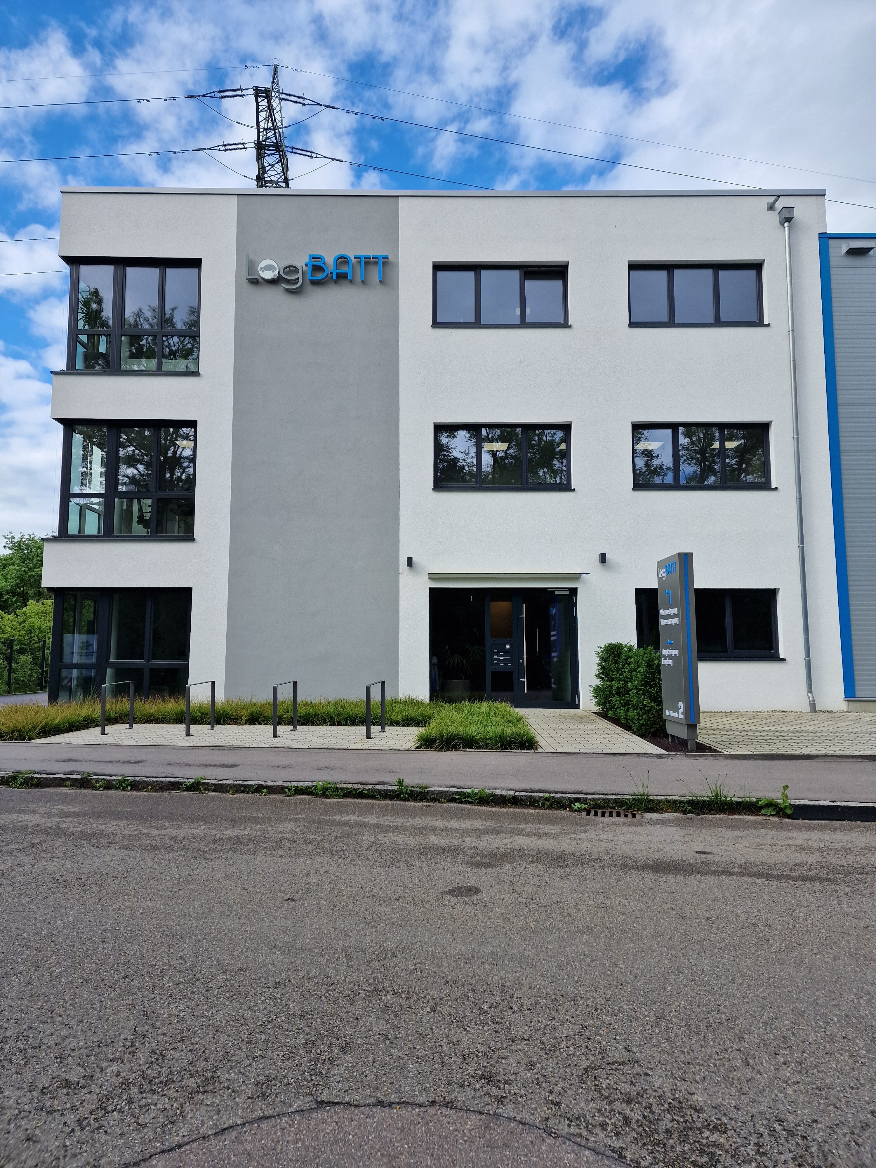 Et moderne kontorbygg med hvit fasade og store vinduer på en overskyet dag.